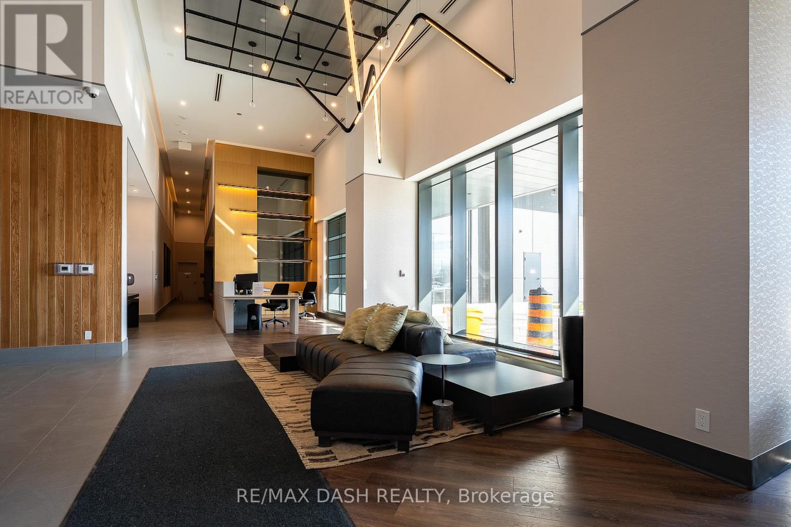 A modern living room with a black rug and a black couch.