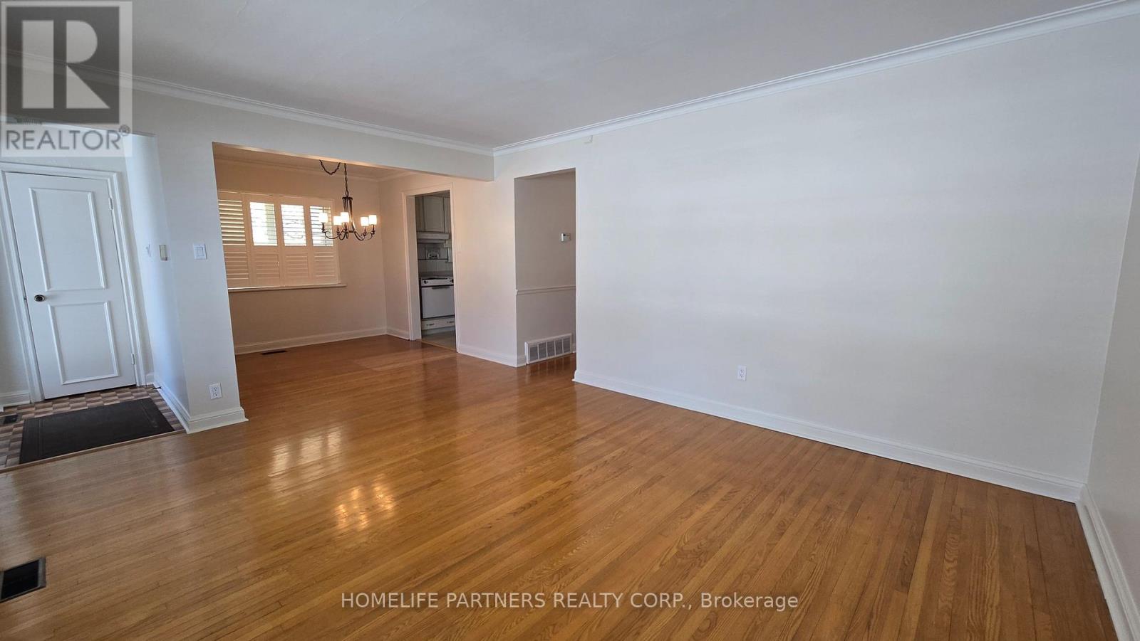A room with wooden floors and white walls, with a door and a window with blinds.