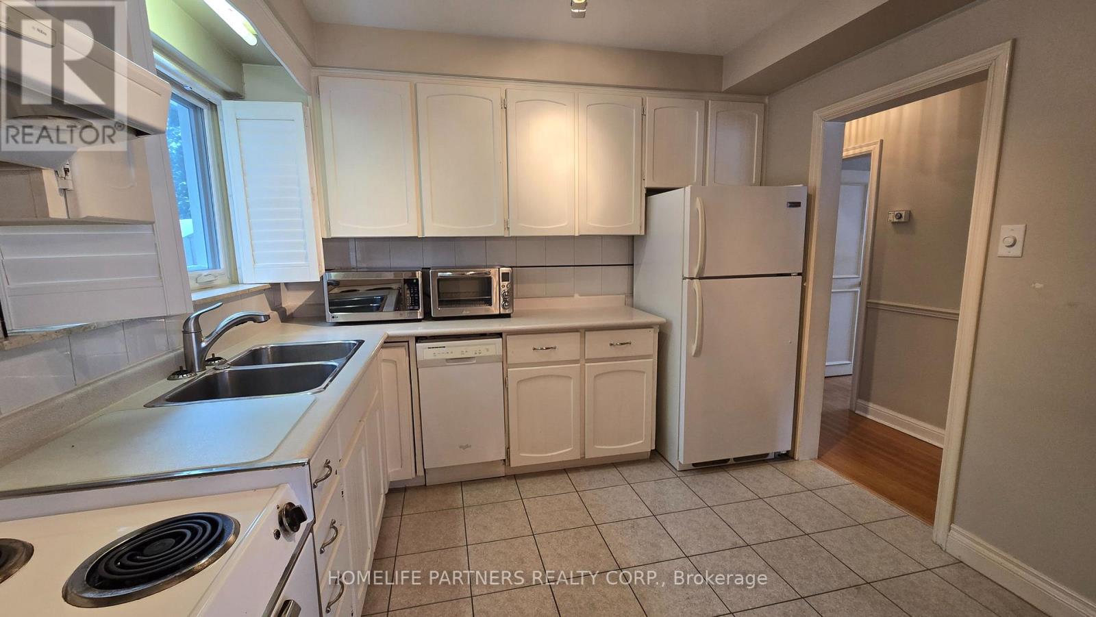 A kitchen with white cabinets and appliances.