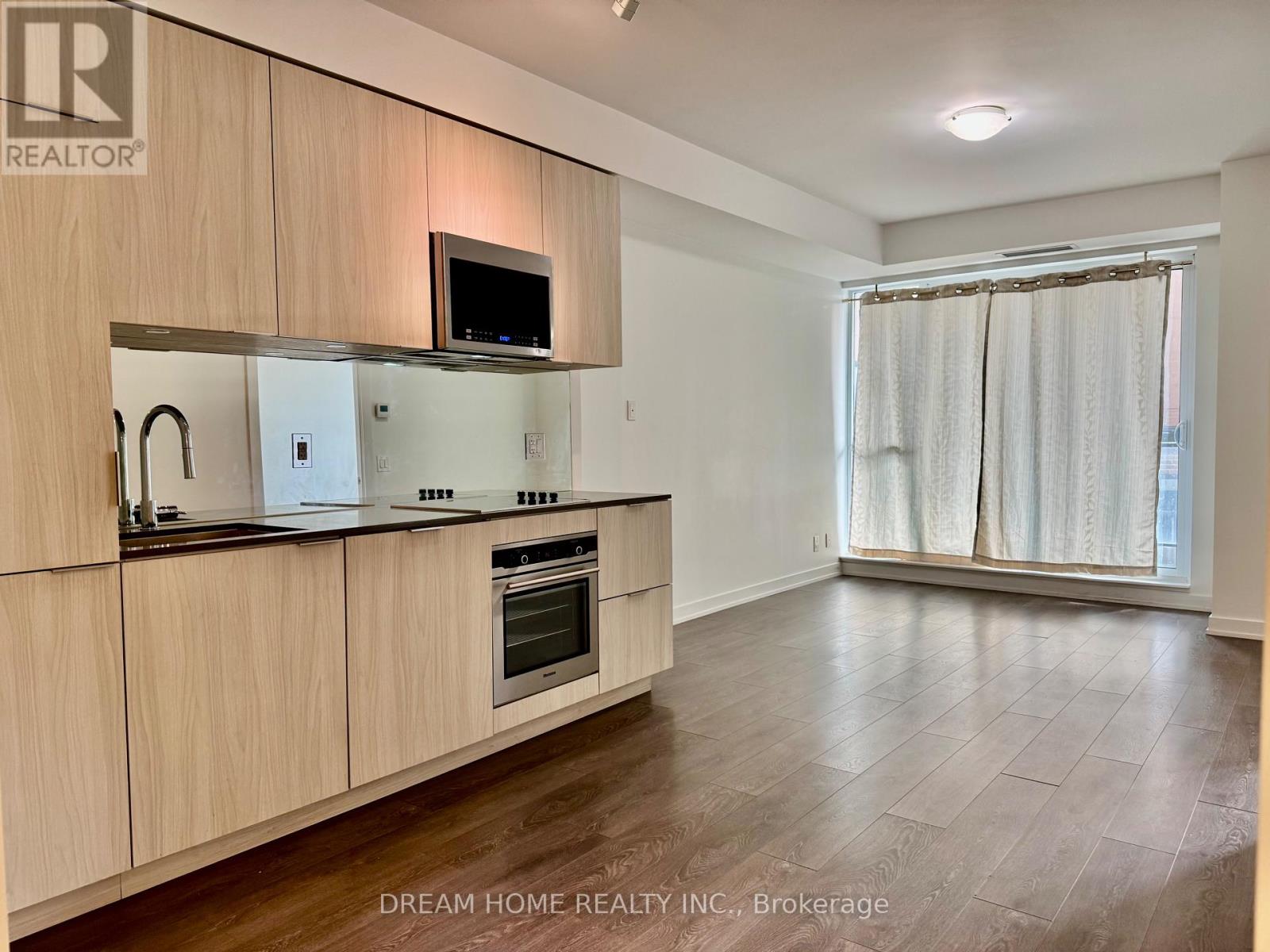 A kitchen with wooden cabinets and a microwave above the stove.