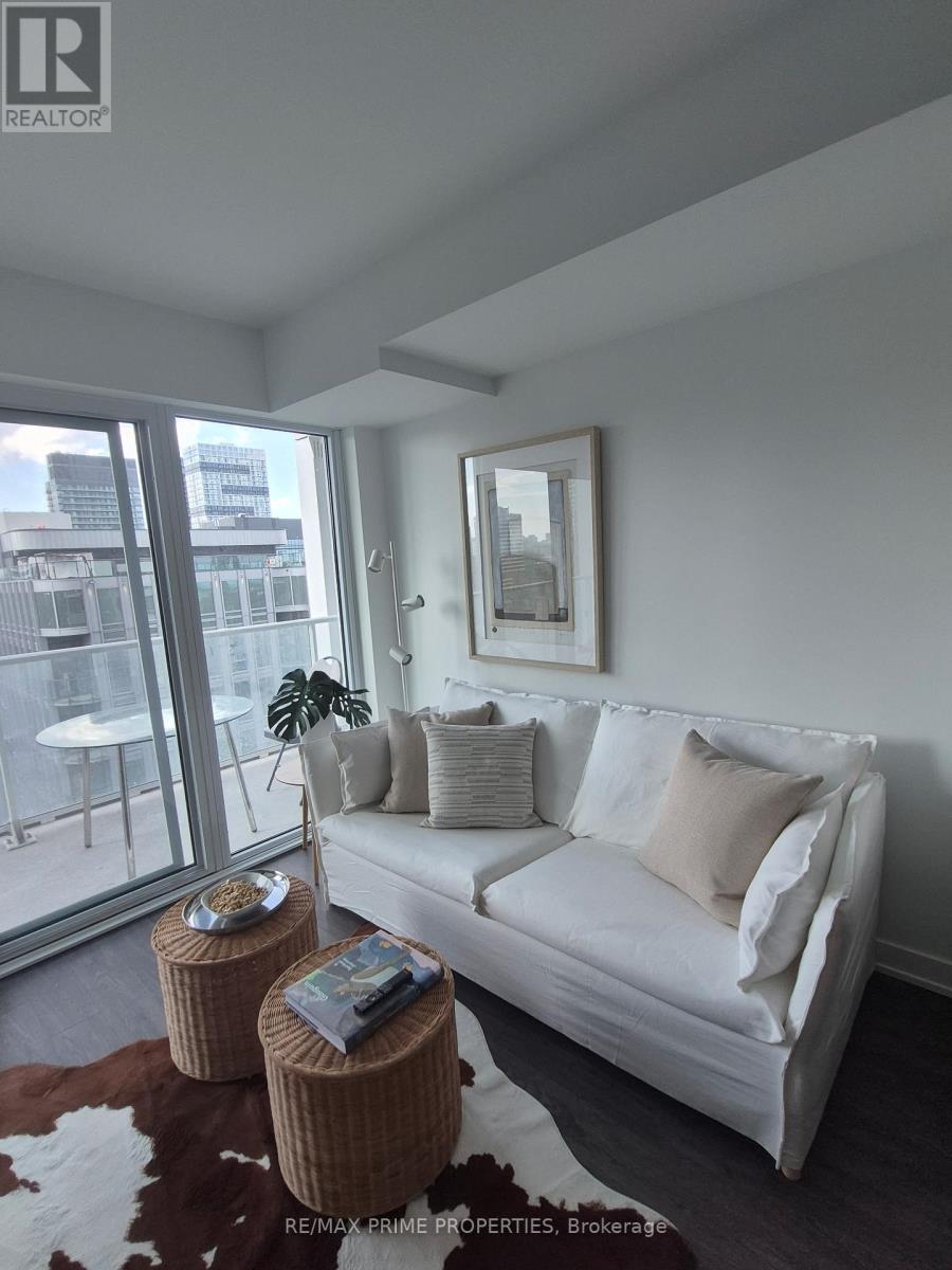 A white couch with a brown ottoman in front of a window.