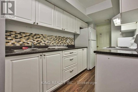 A kitchen with white cabinets and a black counter top.