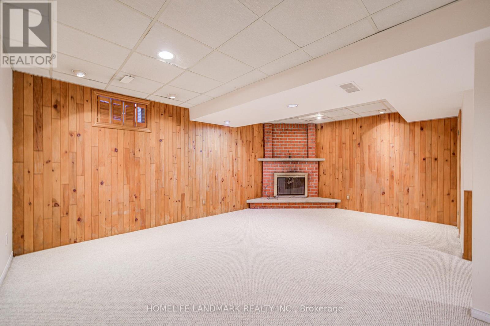 A large empty room with wooden walls and a fireplace.
