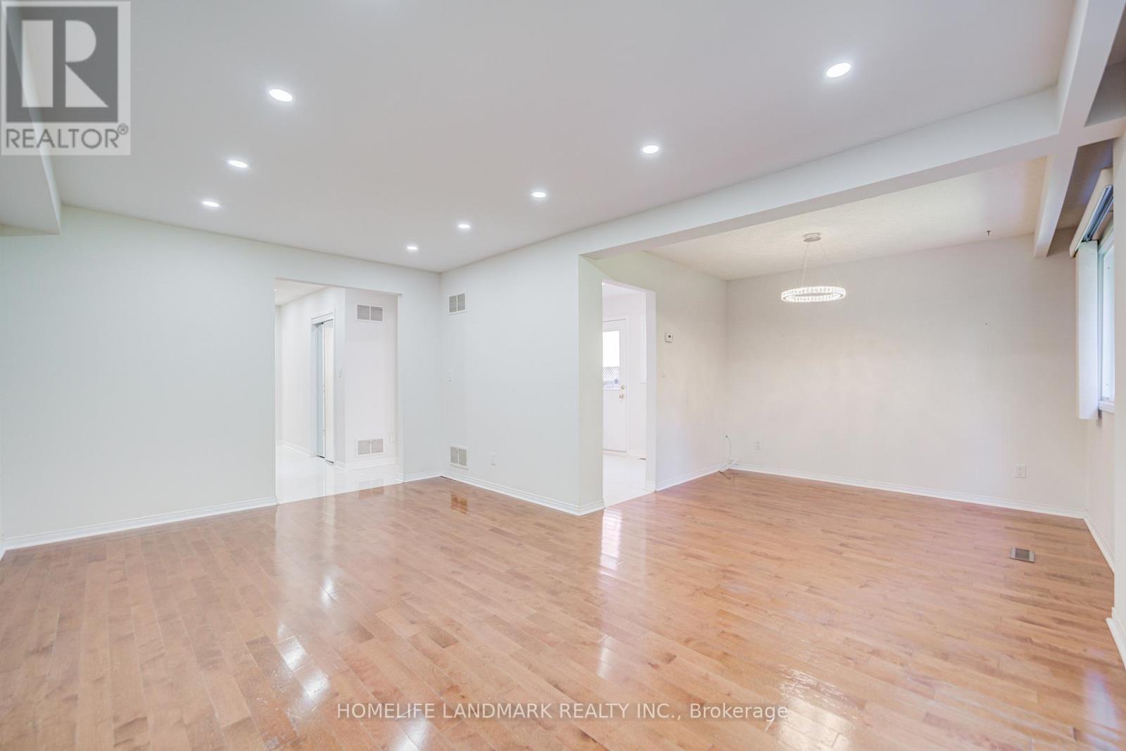 A spacious room with wooden flooring and white walls.