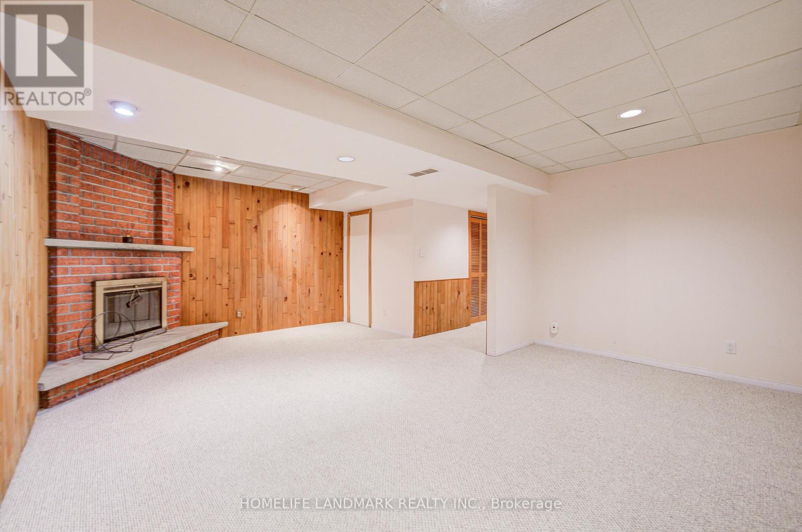 A large, empty room with a fireplace and wooden walls.
