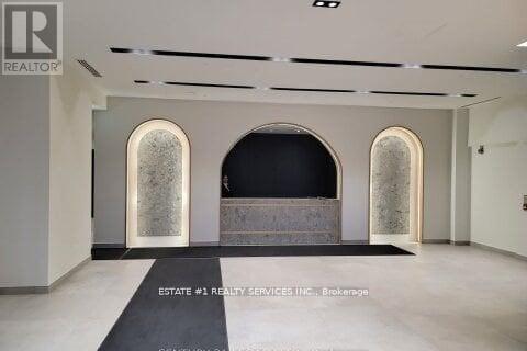 A spacious room with arched windows and a black carpet in the foreground.