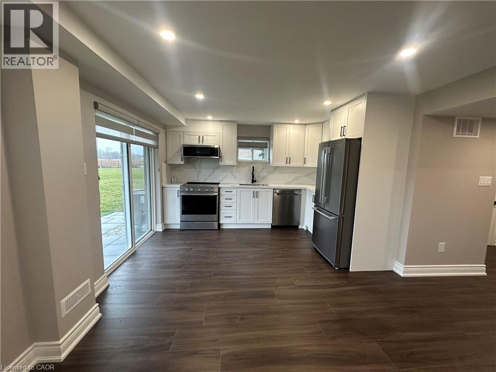 A well-lit kitchen with dark wood floors and white cabinetry.