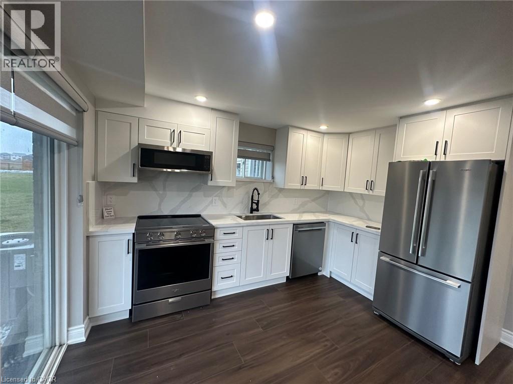 A kitchen with white cabinets and a stainless steel refrigerator.