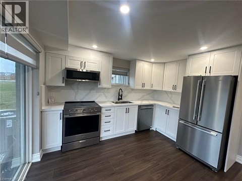 A kitchen with white cabinets and a stainless steel refrigerator.