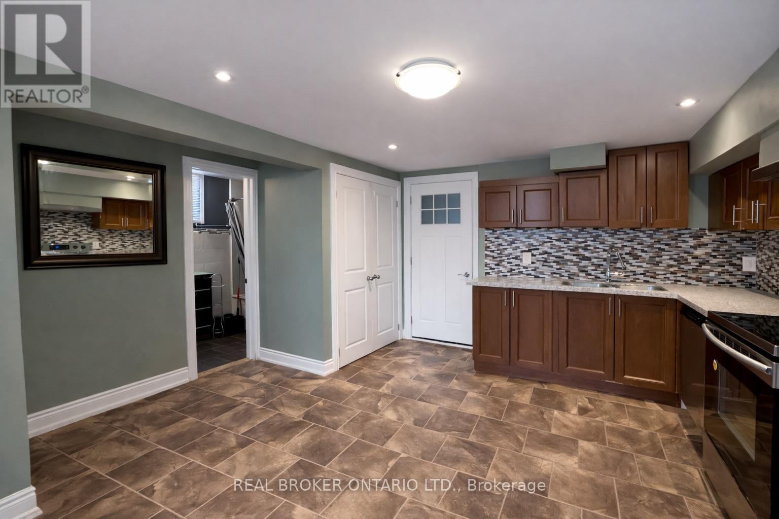 A kitchen with brown tiled floors and a white door.