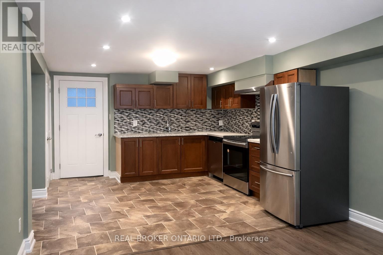 A kitchen with a refrigerator, cabinets, and a backsplash.