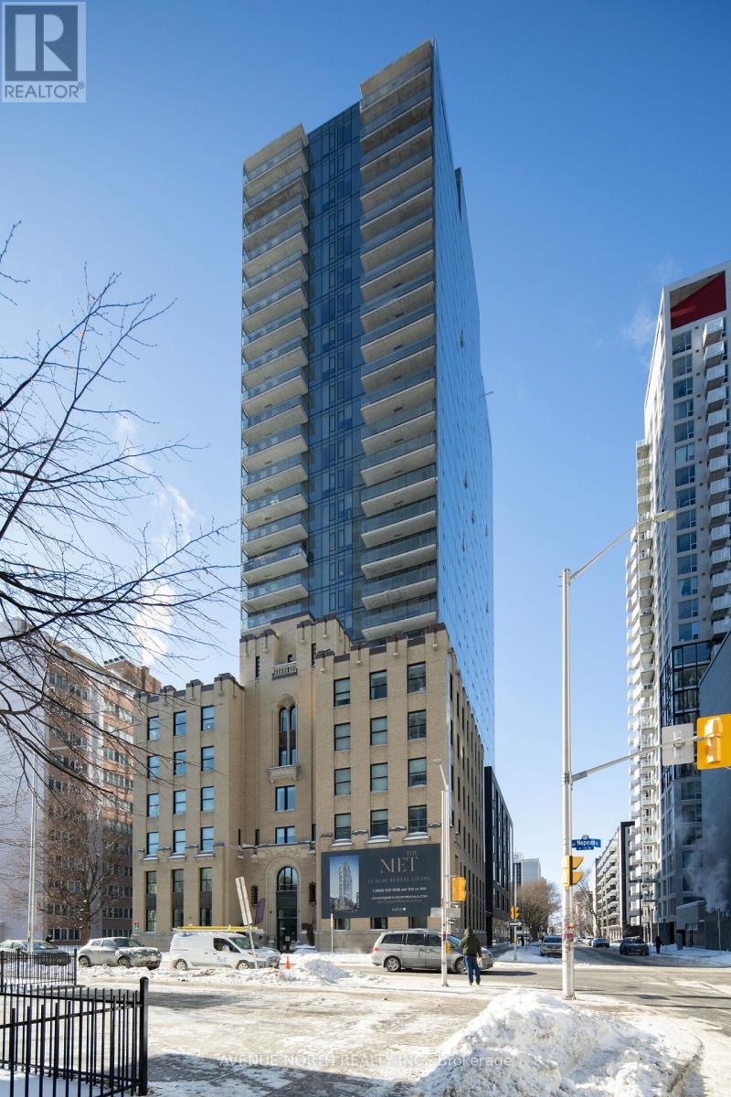 A tall building with a glass facade stands in front of a building with a beige facade.