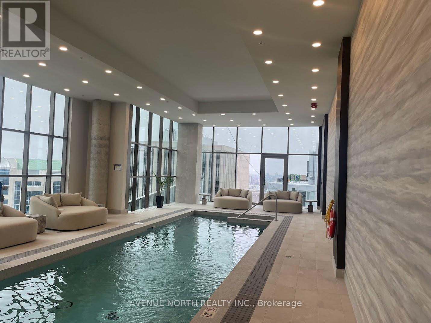 A swimming pool inside a building with a brokerage logo on the wall.