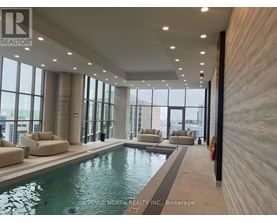 A swimming pool inside a building with a brokerage logo on the wall.