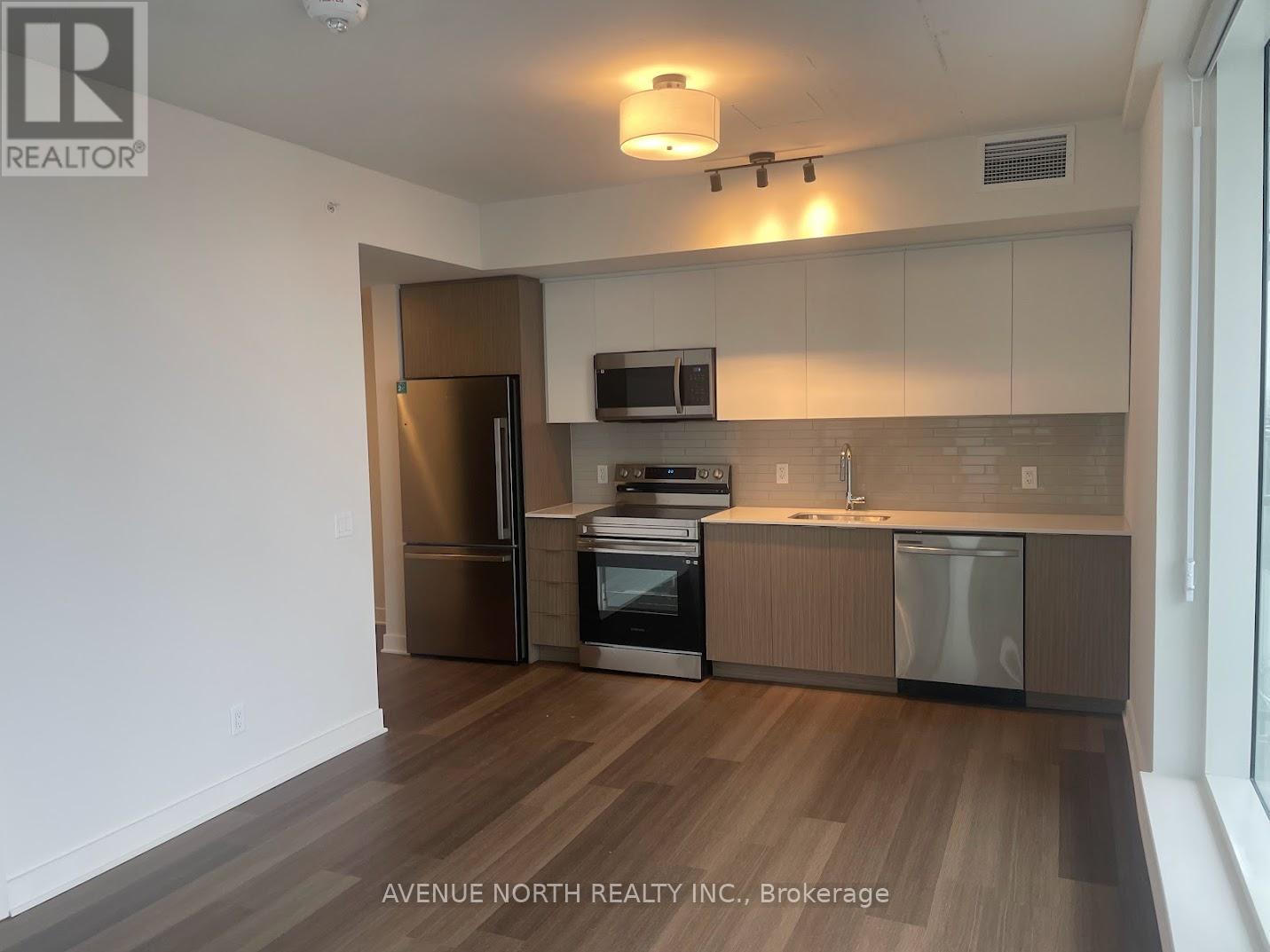A kitchen with wooden floors and stainless steel appliances.
