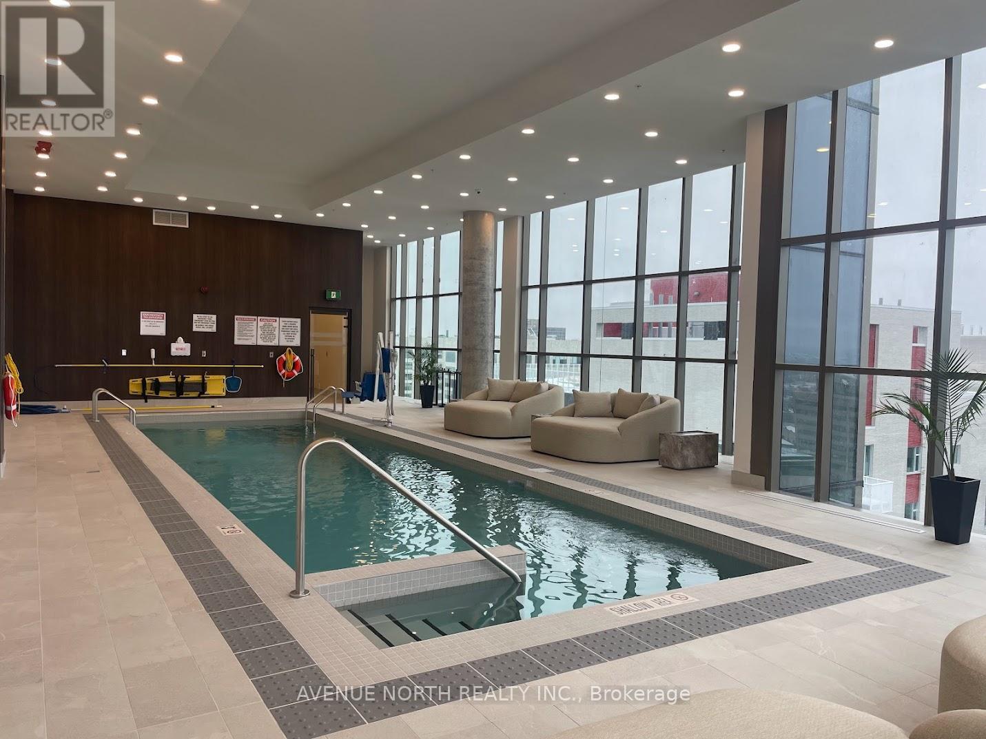 A large indoor swimming pool with a tiled floor and a glass wall.