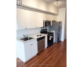 A kitchen with white cabinets and a wooden floor.