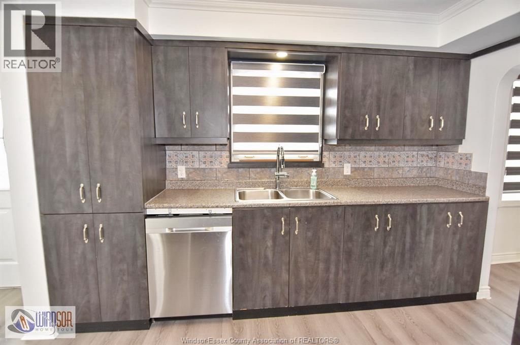A kitchen with dark wood cabinets and a stainless steel dishwasher.