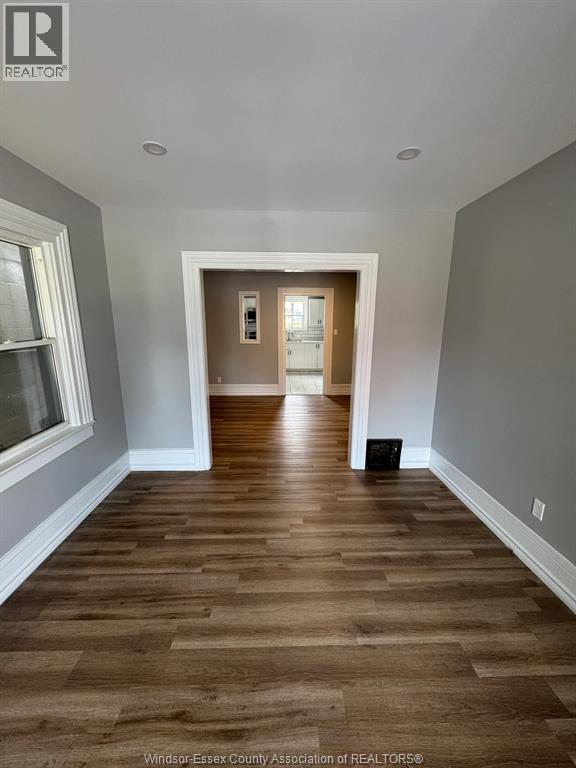 A hallway with wood flooring and white walls.