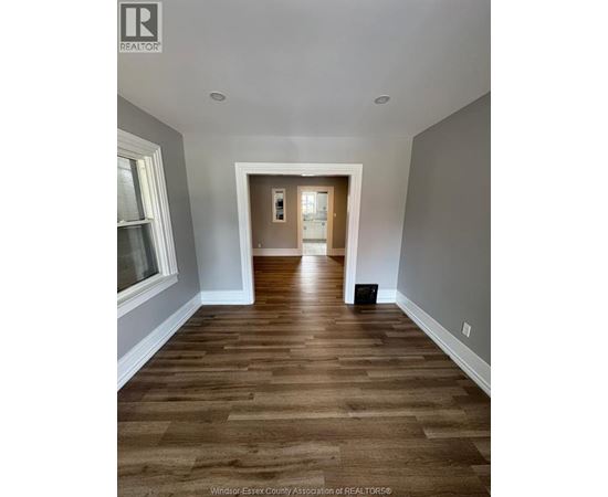 A hallway with wood flooring and white walls.