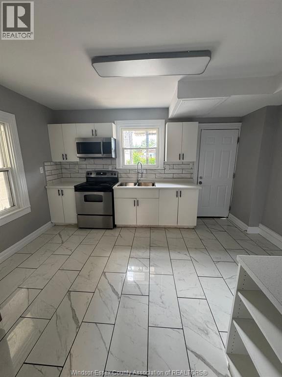 A kitchen with white cabinets and a marble floor.