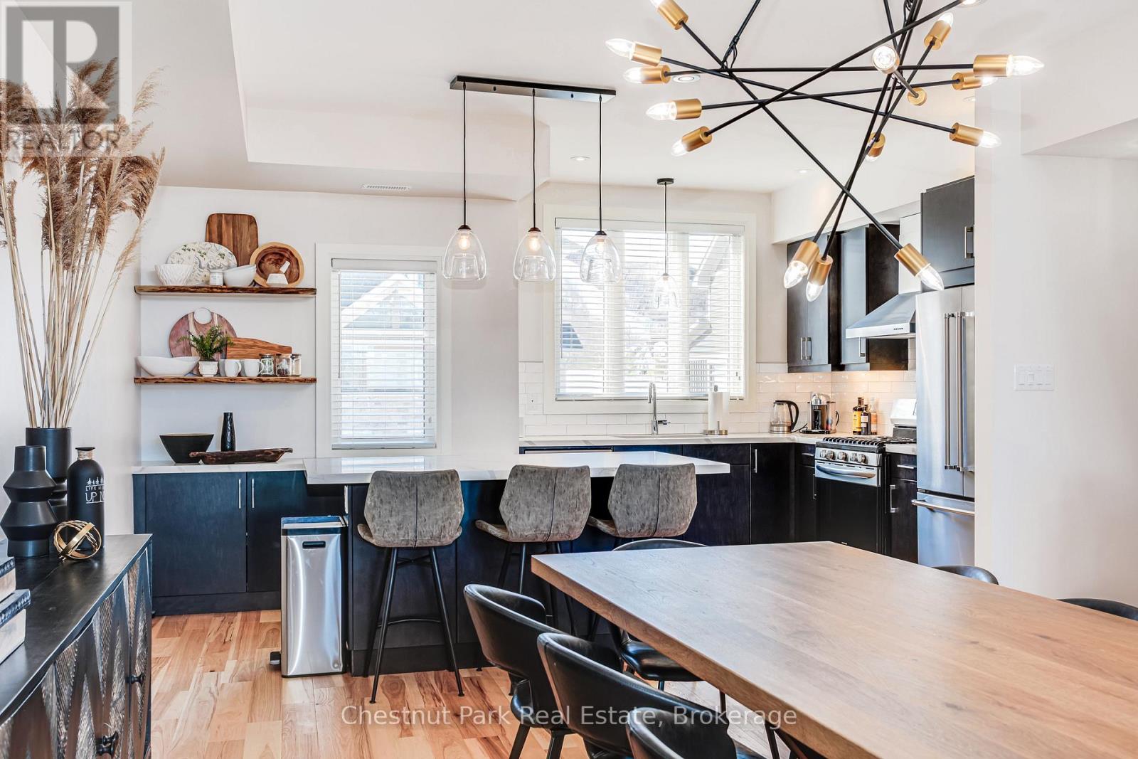 A modern kitchen with a wooden table and black chairs.