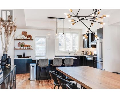 A modern kitchen with a wooden table and black chairs.