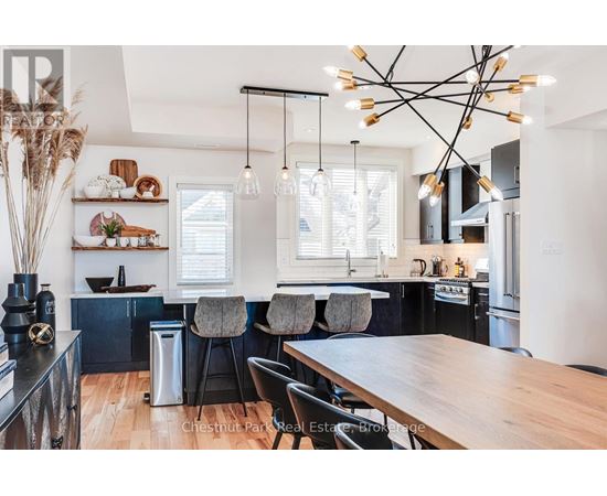 A modern kitchen with a wooden table and black chairs.