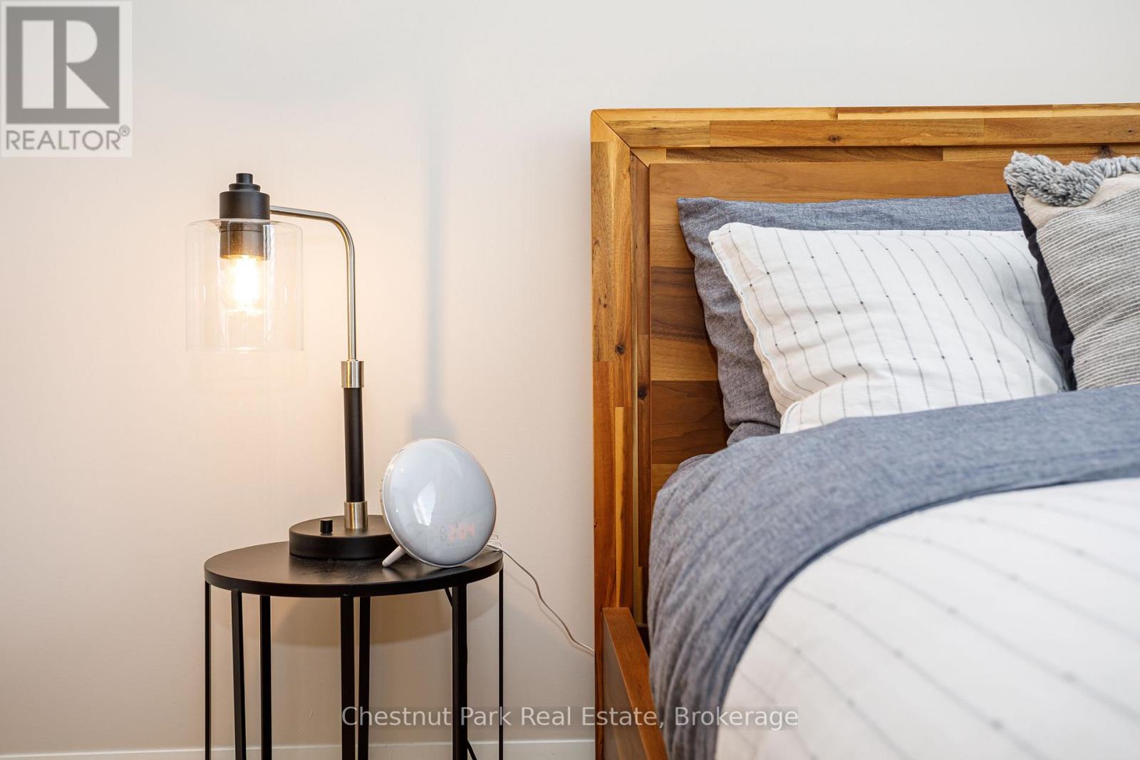 A bedroom with a bed, a table with a lamp and a globe on it.
