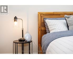 A bedroom with a bed, a table with a lamp and a globe on it.