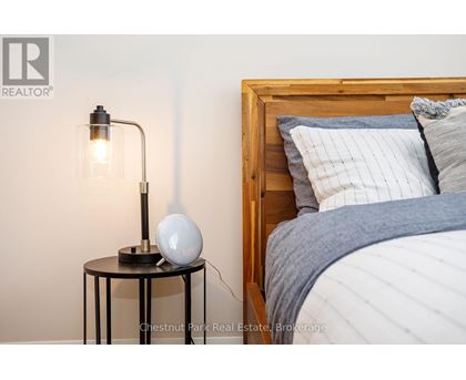 A bedroom with a bed, a table with a lamp and a globe on it.