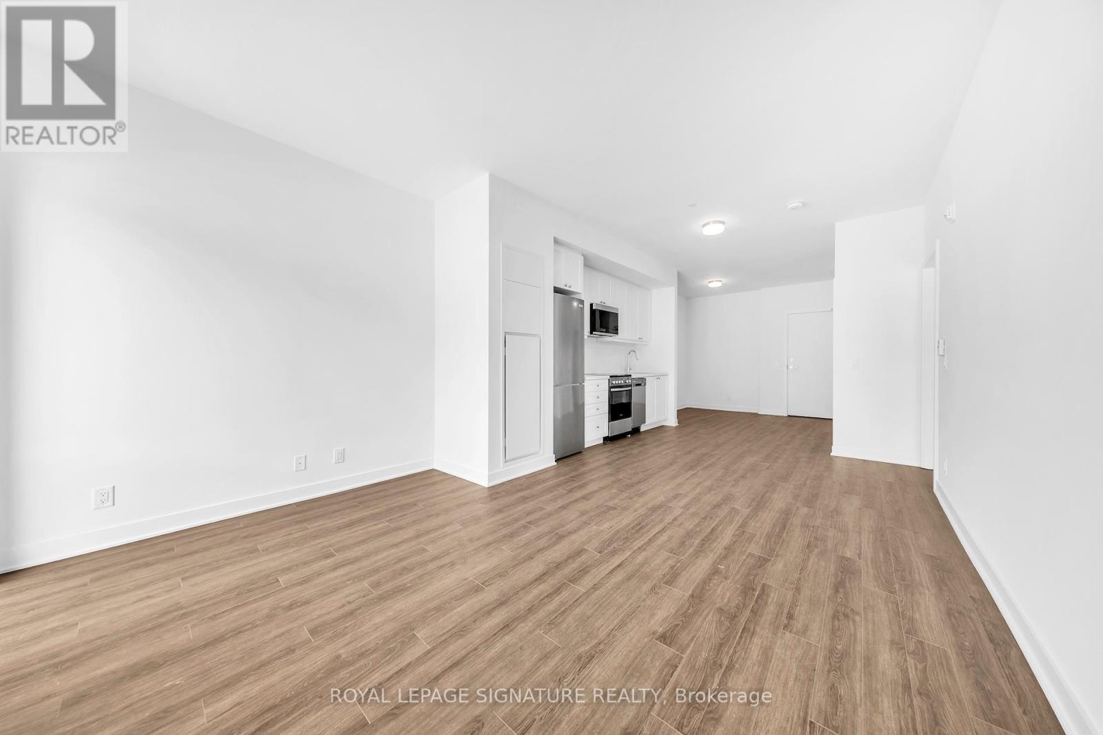 A spacious room with wooden flooring and white walls.