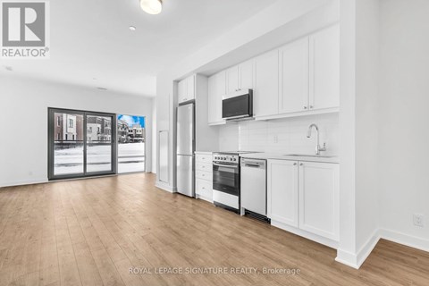 A kitchen with white cabinets and a wooden floor.