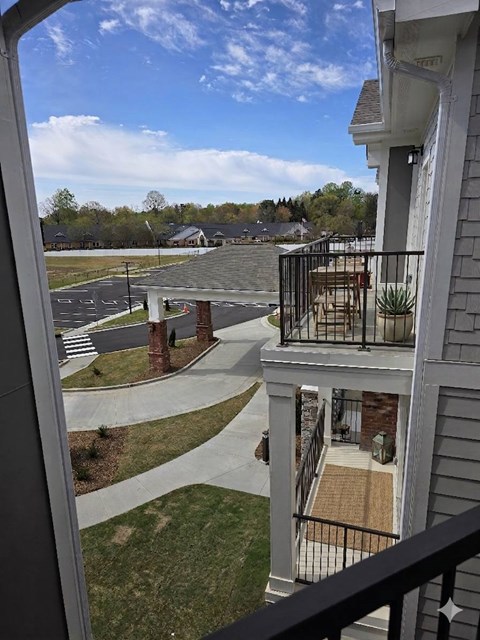 A view from a balcony overlooking a parking lot and a residential area.