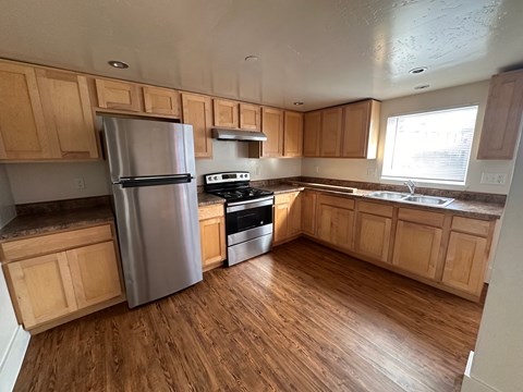 A kitchen with wooden cabinets and a stainless steel refrigerator.