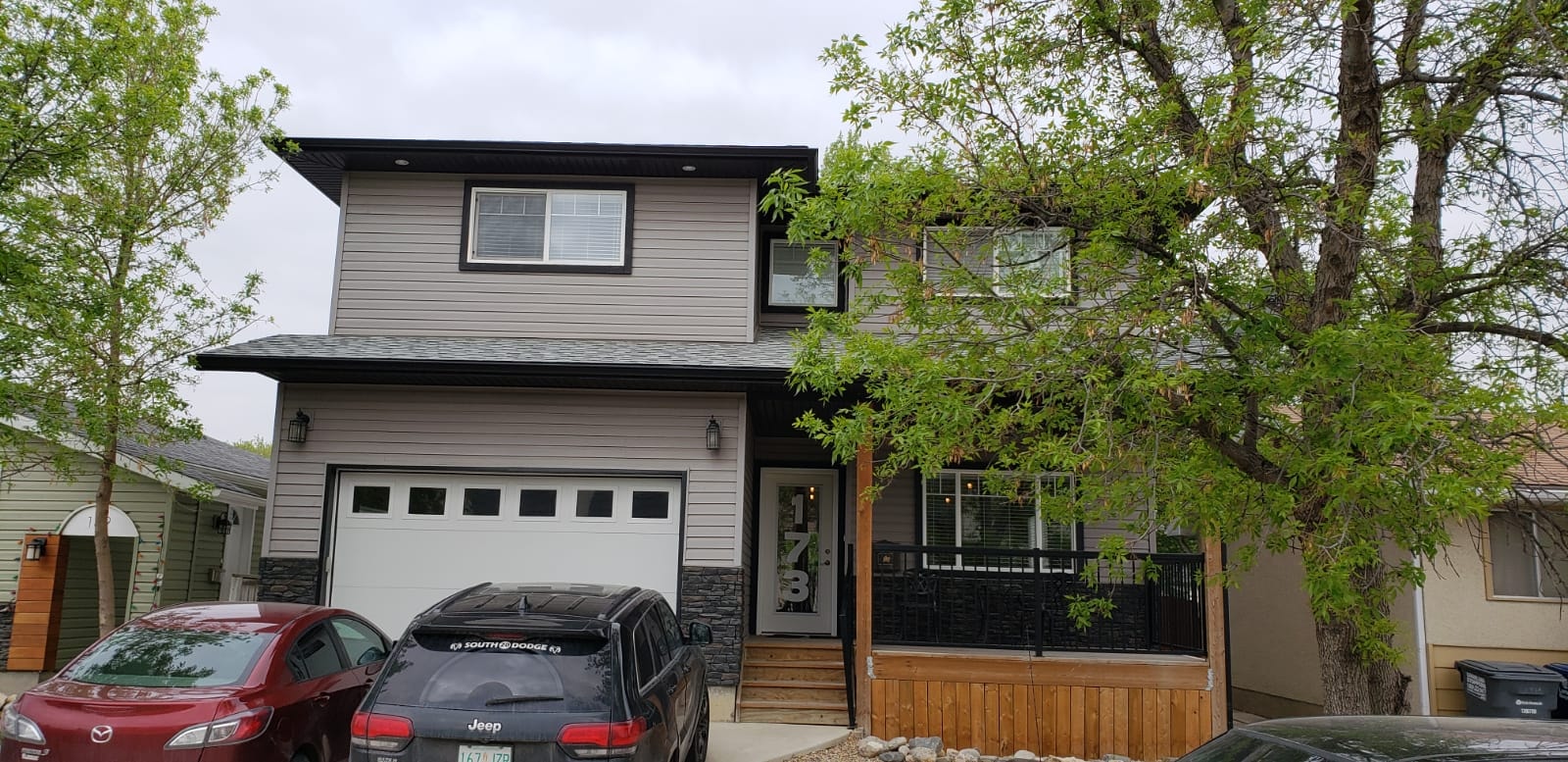 A two-story house with a garage and a car parked in front.
