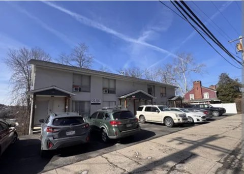 A row of cars parked in front of a building on a sunny day.
