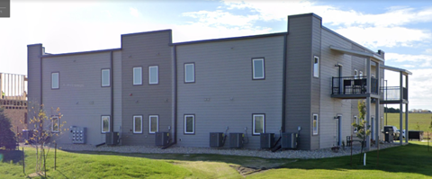 A grey building with a balcony on the top floor.