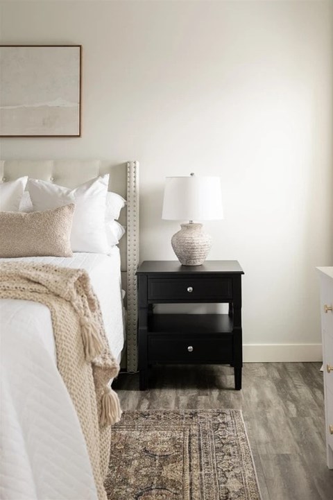 A bedroom with a bed, a nightstand with a lamp, and a rug.