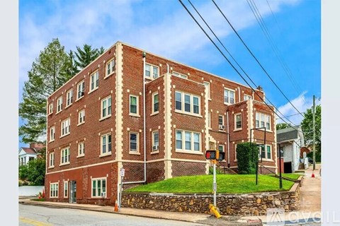 A red brick building with green windows and a stone wall in front.
