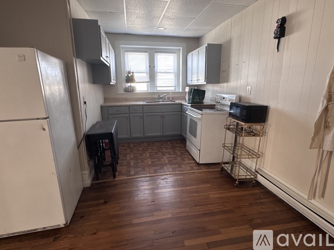 A kitchen with white appliances and wooden floors.