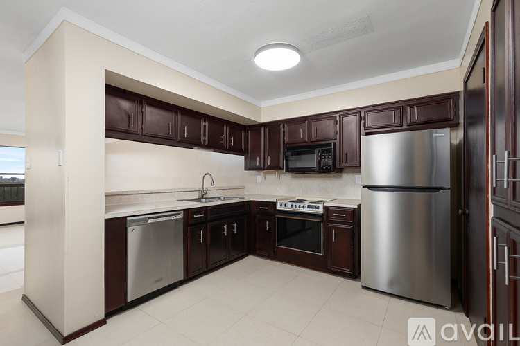 A kitchen with brown cabinets and a stainless steel refrigerator.