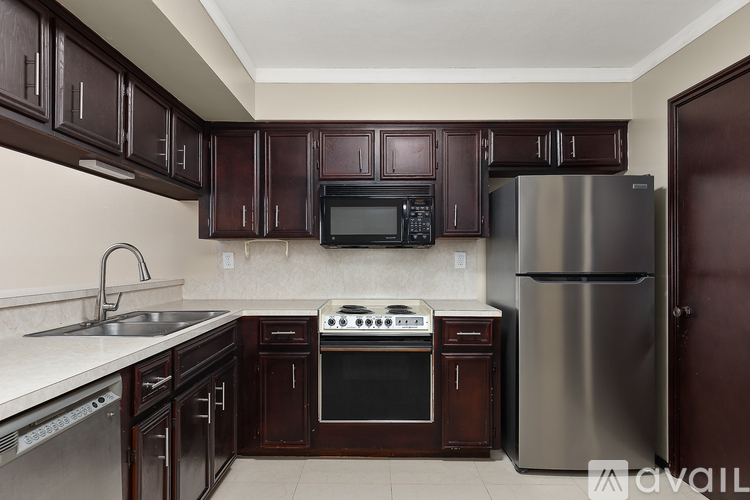 A kitchen with dark brown cabinets and stainless steel appliances.