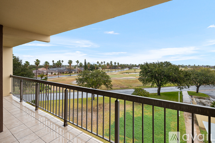A balcony overlooks a green field and trees.