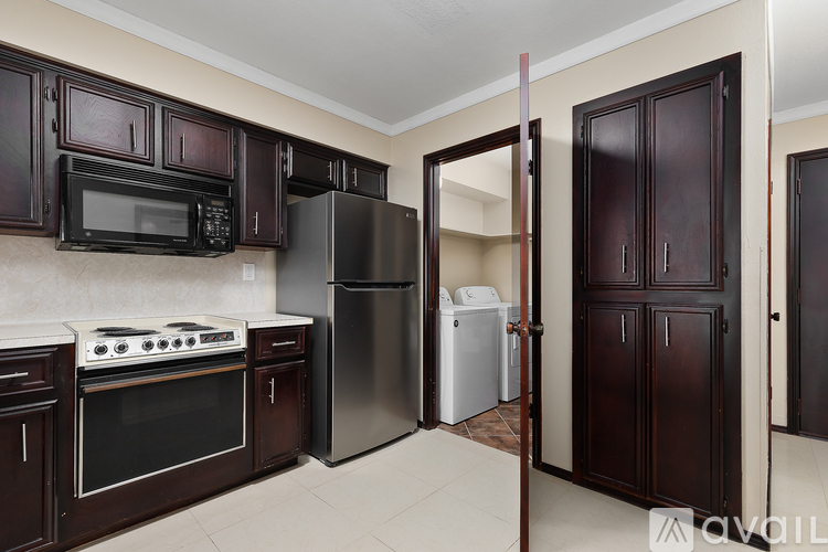 A kitchen with dark brown cabinets and appliances.