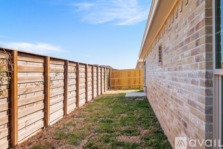 A wooden fence runs along the side of a brick building.
