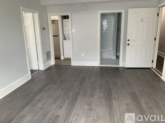 A spacious room with wooden flooring and white walls.