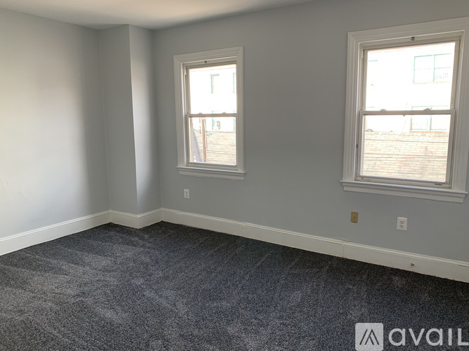 A room with two windows and carpeted floor.