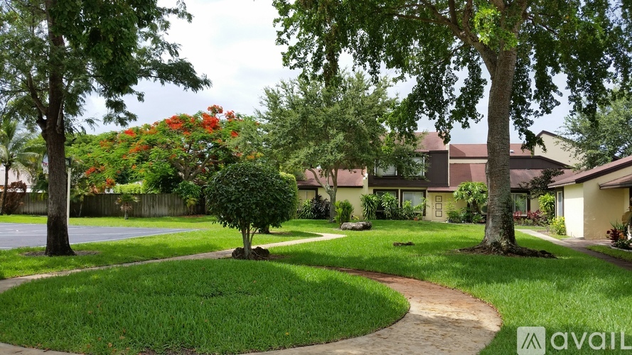 A tree with red flowers is in the middle of a grassy area.