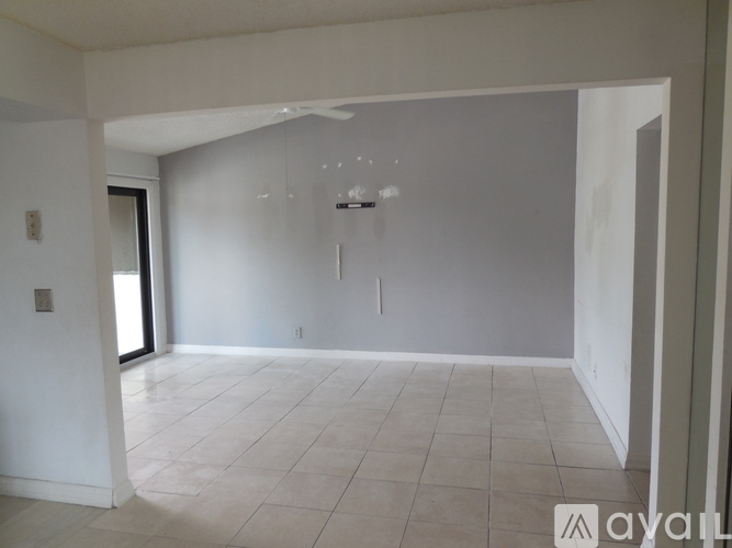 A spacious room with white walls and a tiled floor.